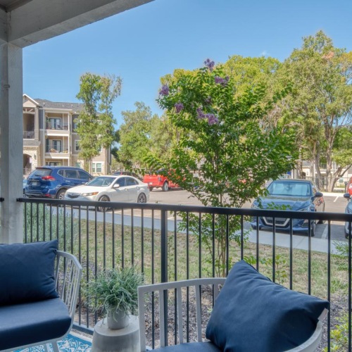 a patio with chairs and a table with cars in the background